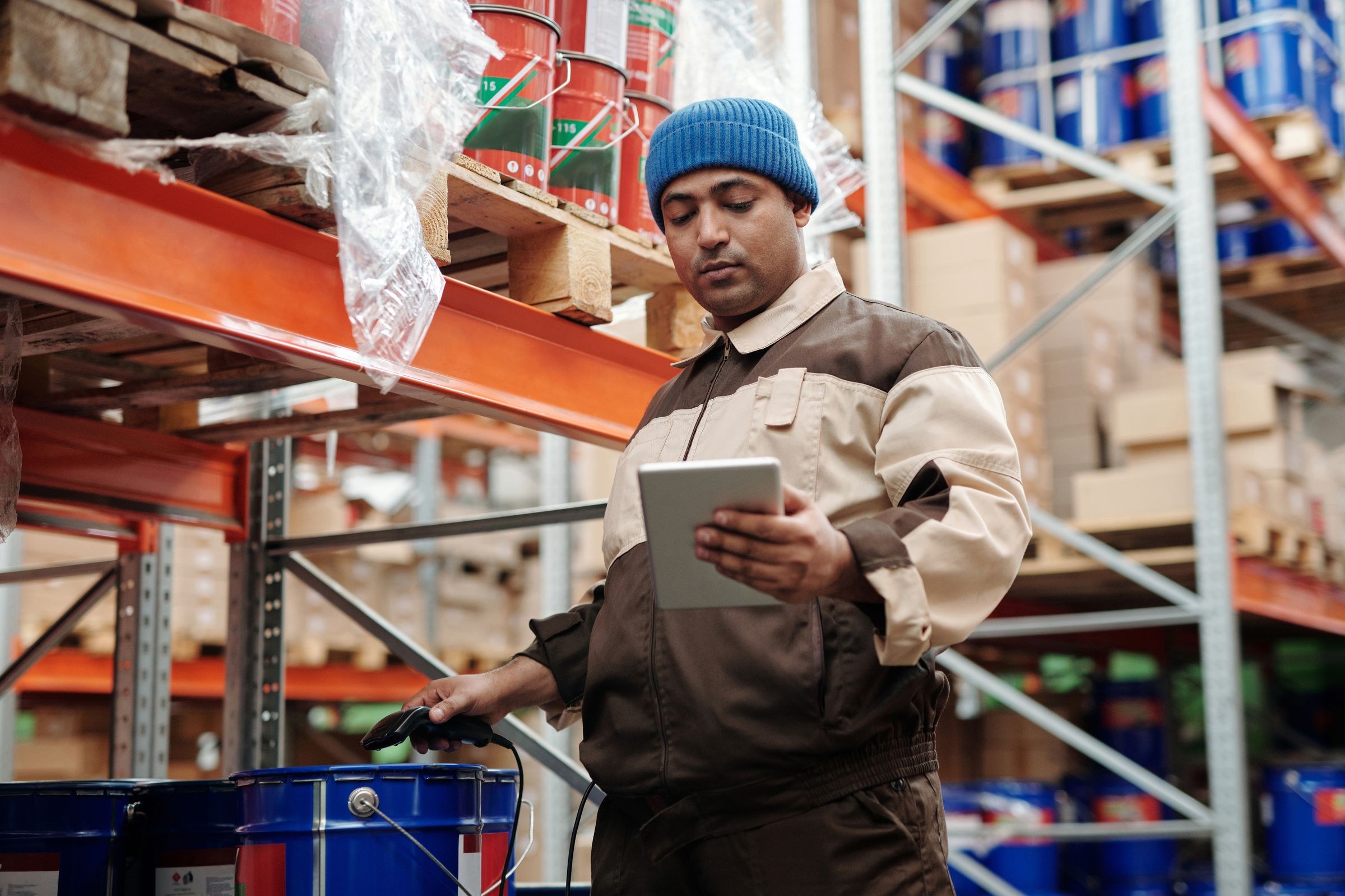 Warehouse worker checking goods with a tablet and handheld scanner